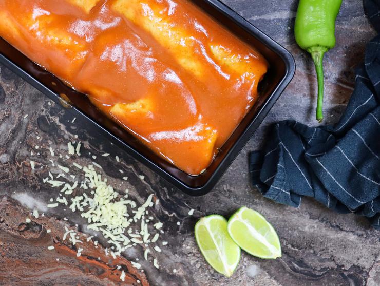 Vegetarian enchilada topped with sauce in baking pan