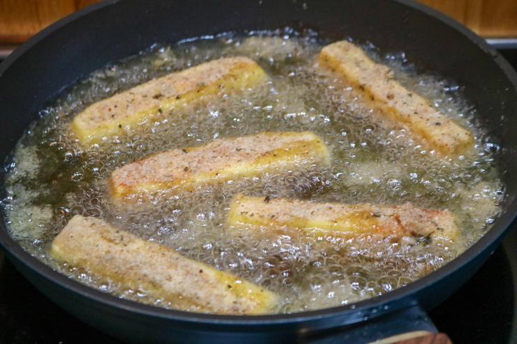 Vegan mazzarella sticks frying in pan